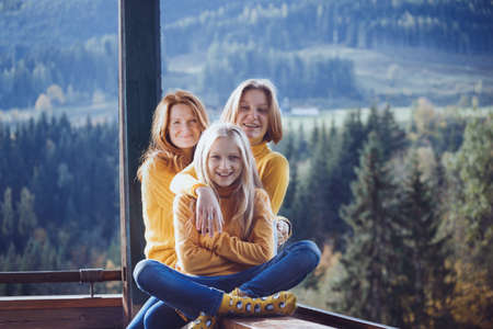 Happy family sitting on the railing on the balcony. morning in a mountain hutの写真素材