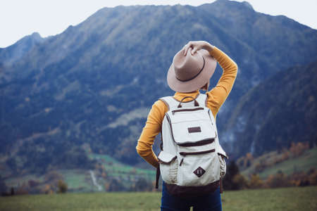 girl with a backpack stands on the meadow in the mountainの写真素材