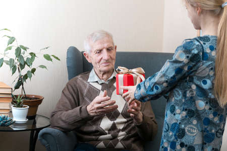 portrait of  senior man.  granddaughter gives grandfather a gift. leisure old manの写真素材