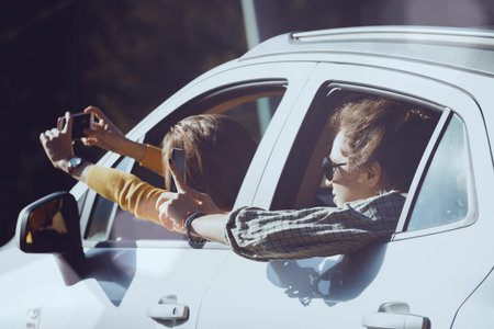 Summer Road Trip. Happy girls travels and taking pictures from the car window.