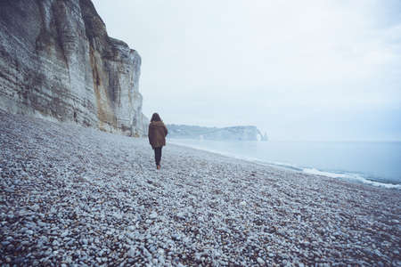 a lonely girl walks along the ocean  in the Etretat. Franceの写真素材