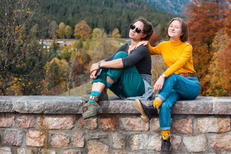 two happy girls tourists sit relax against the backdrop of a mountain landscape. active lifestyleの写真素材