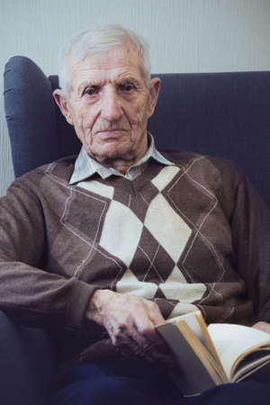 portrait of  senior man  sitting in an armchair and reading books. leisure old manの写真素材