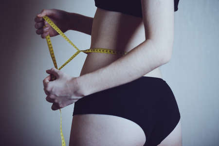 girl measures her volumes with a centimeter. healthy and beautiful body. Female body, slim waist.の写真素材