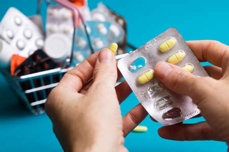 female hands with pills on the background consumer basket products with medicinesの写真素材