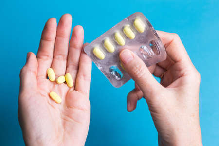 woman pouring a pills from one hand to anotherの写真素材