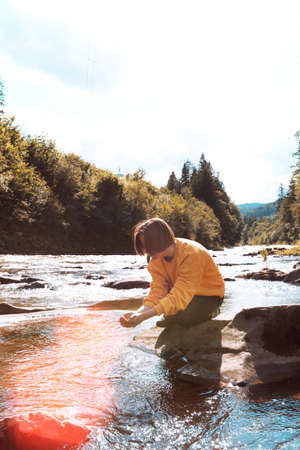 abstract shot of girl hiker drinking a water from the river against a bright sunlightの写真素材