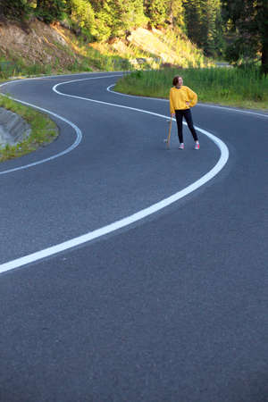Summer Road Trip. beautiful landscape and view of a mountain road. girl rides on a skateboard at the transalpine. Romania.の写真素材