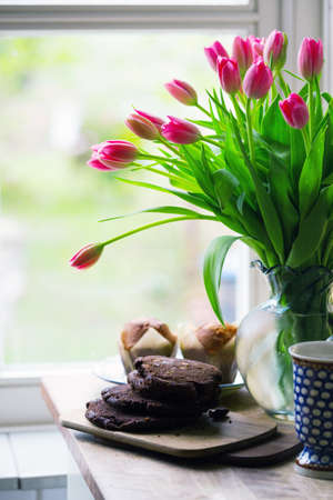 beautiful pink tulips in a vase with cupcakes and cookies in the vintage kitchen. still life
の写真素材