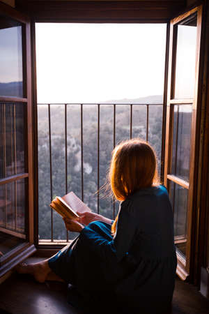 girl is sitting on the floor by the open window and reading a book
の写真素材
