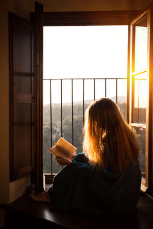 girl is sitting on the floor by the open window and reading a book
の写真素材