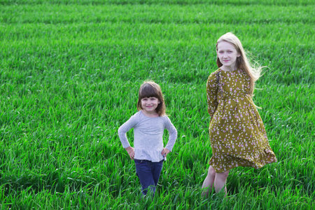 spring  - two beautiful happy girls at the green fieldの写真素材