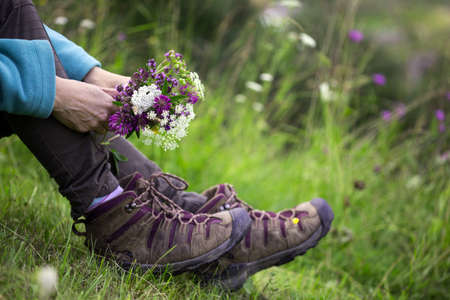 hiking boots close-up. girl tourist in boots and with a bouquet of wild flowers. active lifestyle
の写真素材