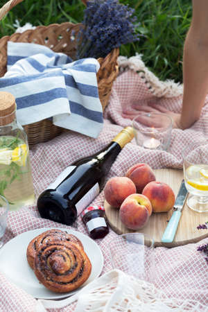 Summer - lemonade with lemon and mint with wine, peaches, cinnamon rolls, candles and a bouquet and a basketの写真素材