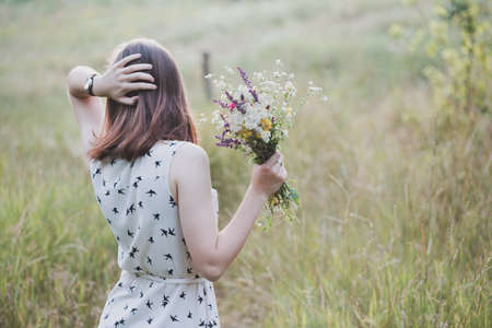 Summer - girl with a bouquet walks through the meadow. summer mood and inspirationの写真素材