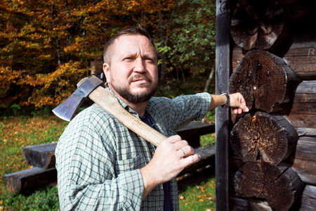 man with an ax near a wooden house in the mountainsの写真素材