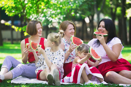 Summer -  big happy family at a picnic with watermelon.  Fun juicy summer and bright family picnicのeditorial素材