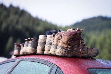 a lot hiking boots close-up stand on the roof of the car after tracking and beautiful mountain...