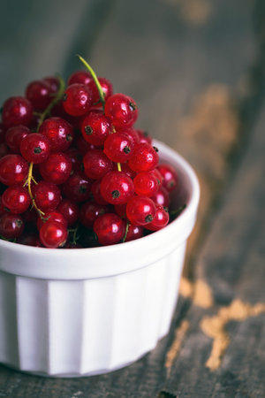 red currants in a bowl on a wooden background