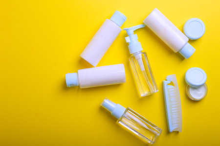 travel beauty kit on a yellow background. shampoo, balm, cream and lotion in vials
