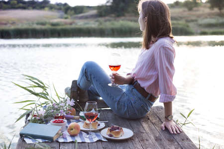 girl enjoying picnic on a wooden pier on a shiny summer river shoreの写真素材