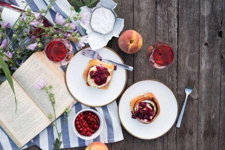 Summer still life-   picnic on a wooden pier. wine, sinabones, peaches, a book with a lake viewの写真素材