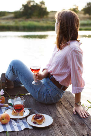girl enjoying picnic on a wooden pier on a shiny summer river shoreの写真素材