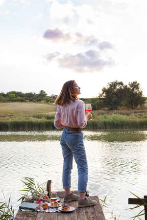 girl enjoying picnic on a wooden pier on a shiny summer river shoreの写真素材