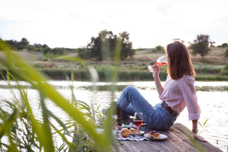 girl enjoying picnic on a wooden pier on a shiny summer river shoreの写真素材