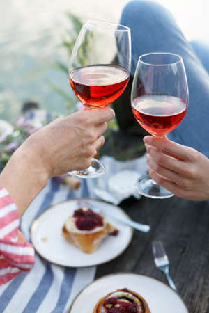 two girls enjoying picnic on a wooden pier on a shiny summer river shoreの写真素材
