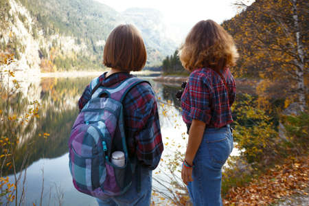 mountain trip. two happy girls on the background of a mountain lake and mountains in the backgroundの写真素材