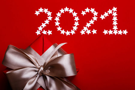 christmas background. on a red background an inscription with asterisks 2021 and a gift