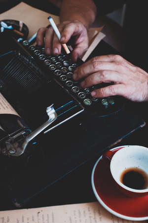 a beautiful old retro typewriter close-up, hands and a cup of coffeeの写真素材