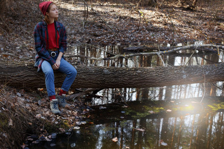beautiful stylish girl holding a camera in the forest. wild conditions