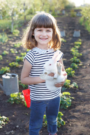 girl and rabbit  in the garden. happy childhood in the villageの写真素材