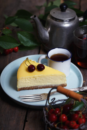 cheesecake on a plate and cup with cherries and a bouquet of peonies nearby