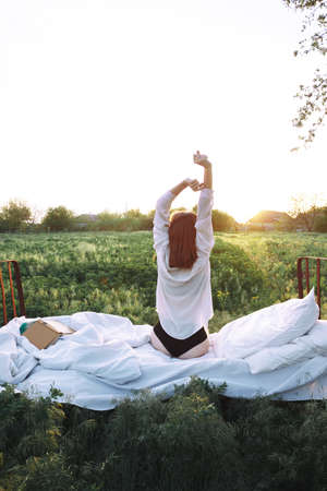 girl resting in the bed in a green field. healthy sleep in nature. Ecotourismの写真素材