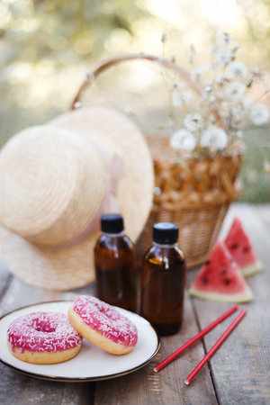 Summer still life-   picnic in the village. donuts, cold coffee, watermelon, book, hat and basket