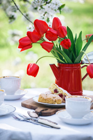 steel life - breakfast in the spring garden. table with white tablecloth served for tea drinking,...