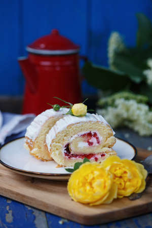 biscuit roll with strawberries. a piece of dessert on a plate. rose and strawberry for decorationの写真素材
