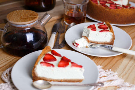 delicious and beautiful breakfast. cheesecake with strawberries on a wooden background with a bouquet of peoniesの写真素材