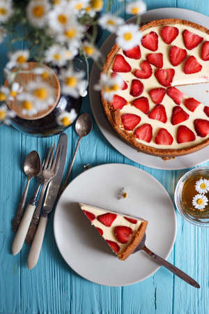 delicious and beautiful breakfast. cheesecake with strawberries on a wooden background with a bouquet of daisyの写真素材