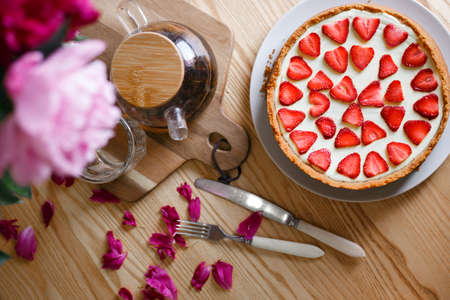 delicious and beautiful breakfast. cheesecake with strawberries on a wooden background with a bouquet of peoniesの写真素材