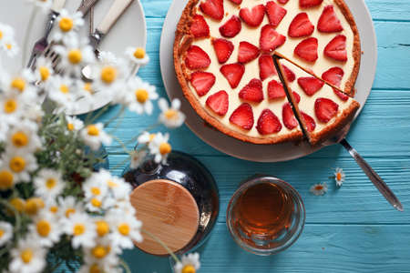 delicious and beautiful breakfast. cheesecake with strawberries on a wooden background with a bouquet of daisyの写真素材