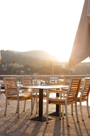 cafe on the waterfront. empty tables, chairs and a bay with boats in the background