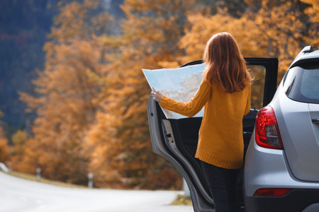 travel by car. Road trip -  tourist girl with a map is standing near the car. Austria