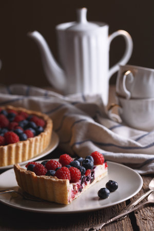 berry pie with raspberries and blueberries on the background of retro cups and teapotの写真素材