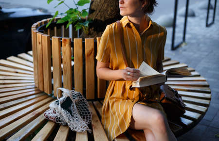 city Style. a girl sits on a bench and reads a bookの写真素材