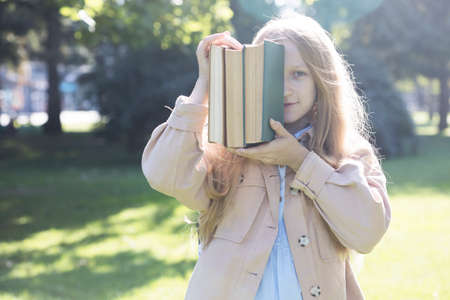 beautiful fun schoolgirl with a backpack and books outdoorの写真素材
