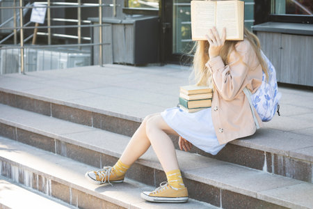 girl with books sitting on the stepsの写真素材